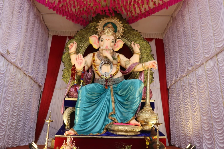 a statue of lord ganesh is placed next to a red and white curtain