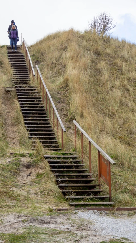 two people walking up stairs to the top of a hill