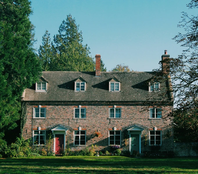 a brick building with large windows and doors is surrounded by trees