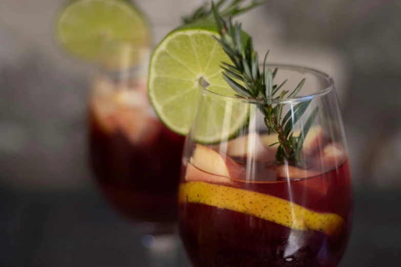 two glasses filled with wine, ice and lemon wedges