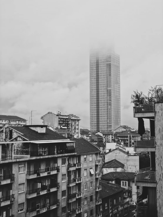 black and white pograph of some buildings with fog rolling around the tops