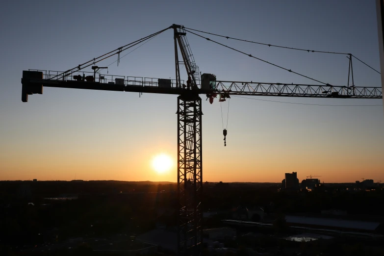 a crane sitting above the city at sunrise