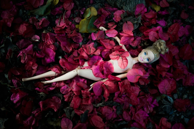 a body doll is laying on a bed of pink flowers