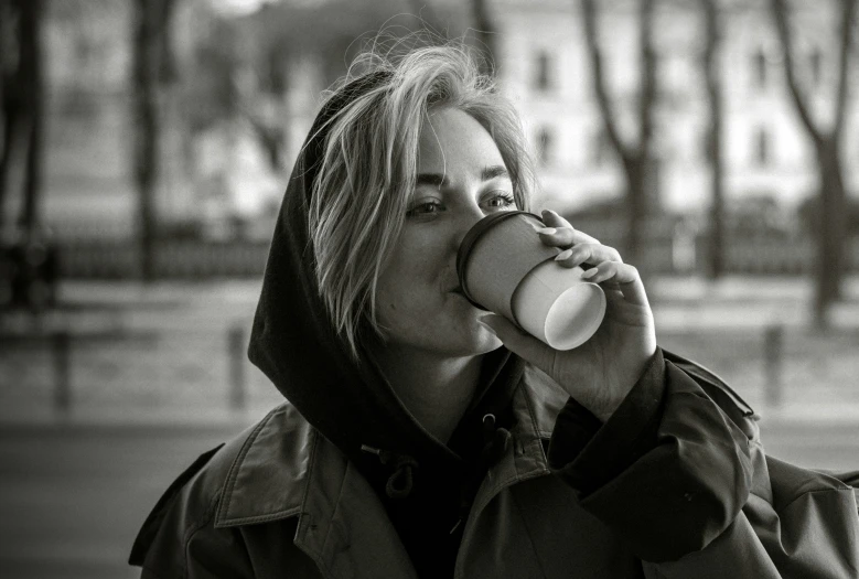 a woman sips her coffee while walking in the city