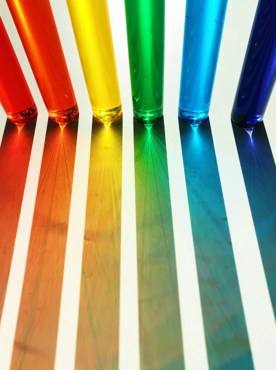 a rainbow - colored glass cup and four striped bottles are shown