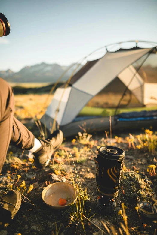 a man is sitting in the grass with his feet up and an open tent