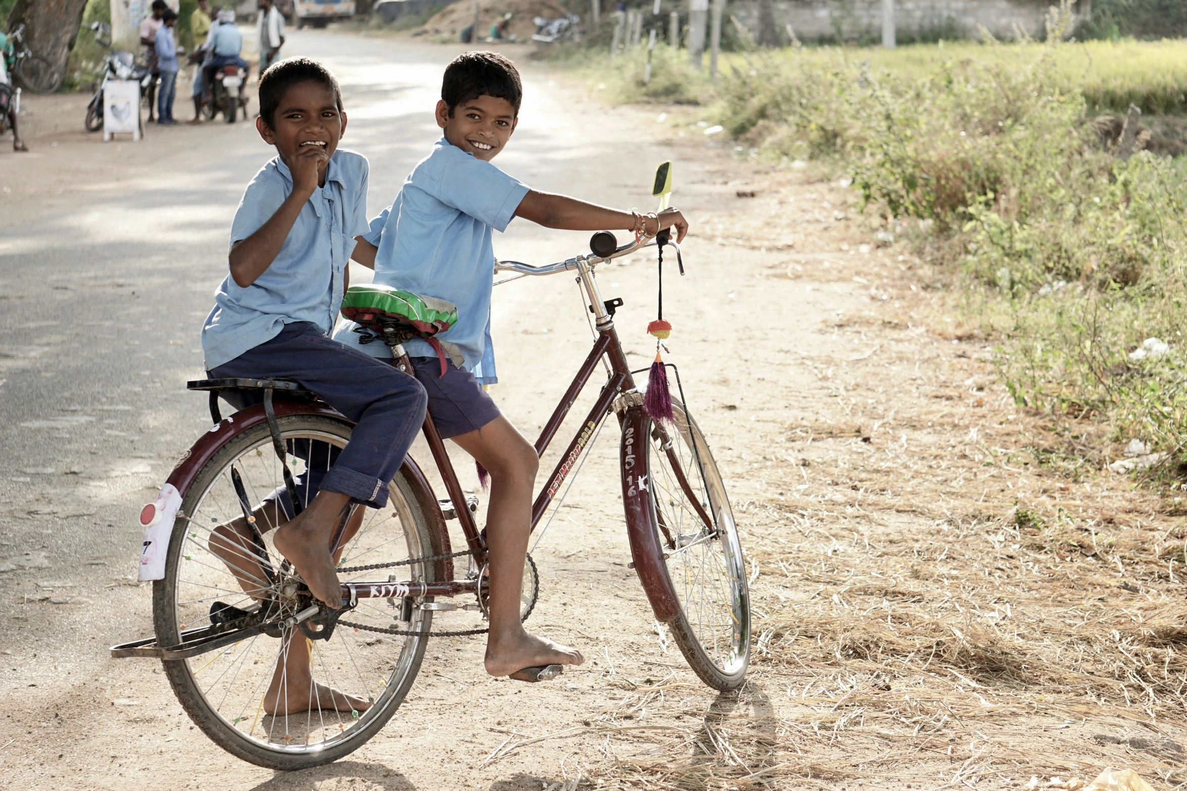 a boy and girl riding on the back of a bike