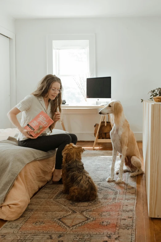 a woman is sitting with two dogs in her bedroom