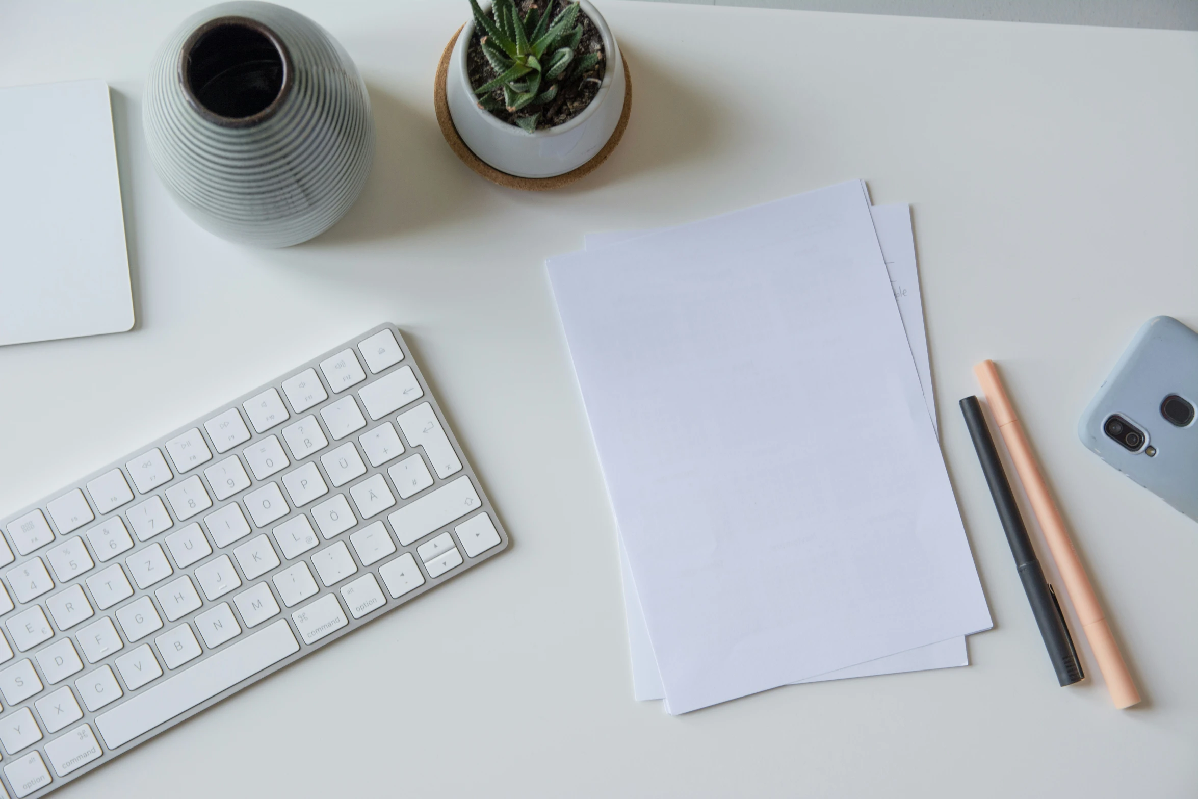 a desk with a keyboard, mouse and plant