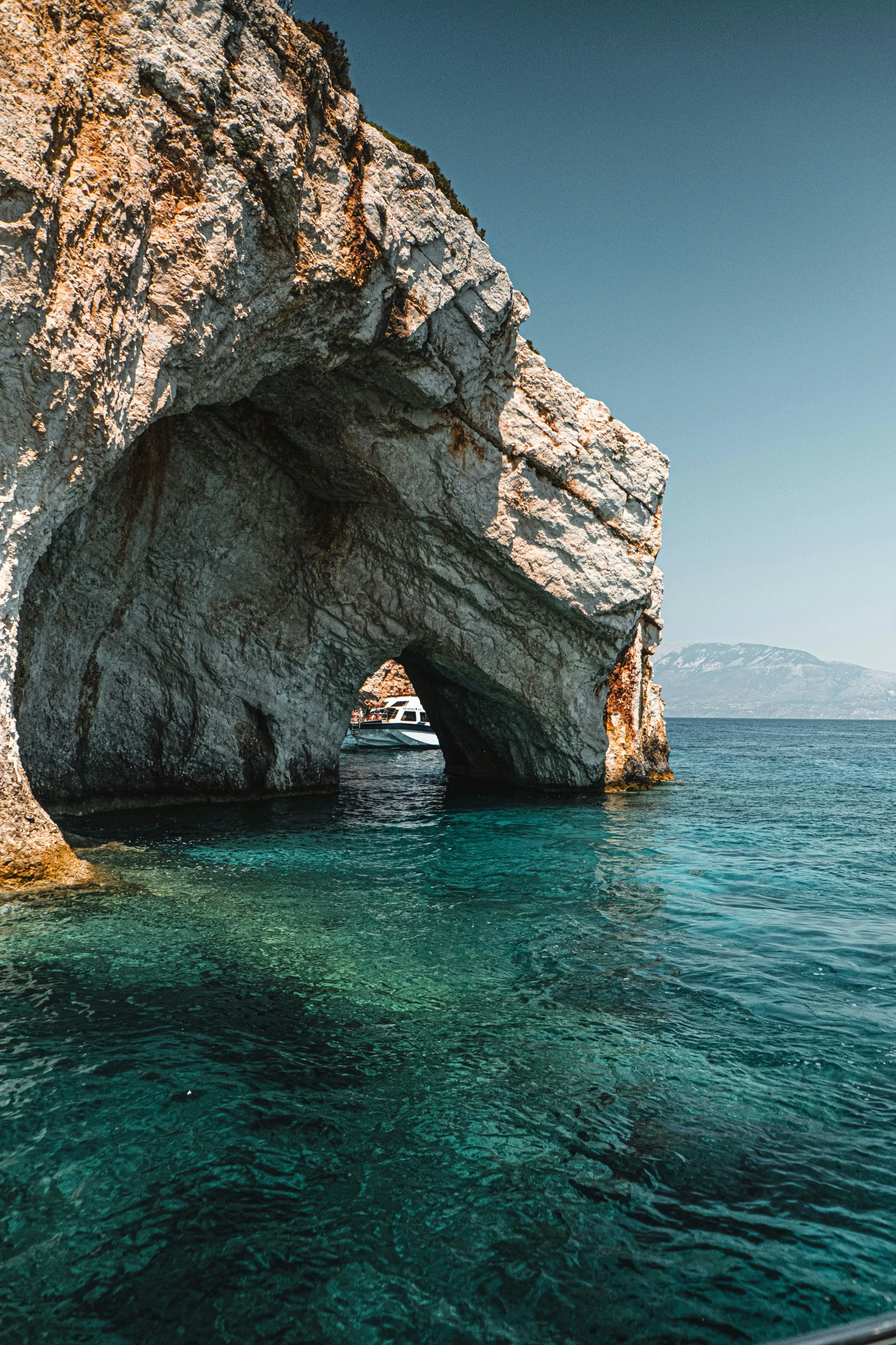 a boat is sailing away from a large rock formation