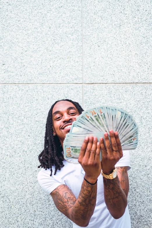 a smiling young man holding a fan of money