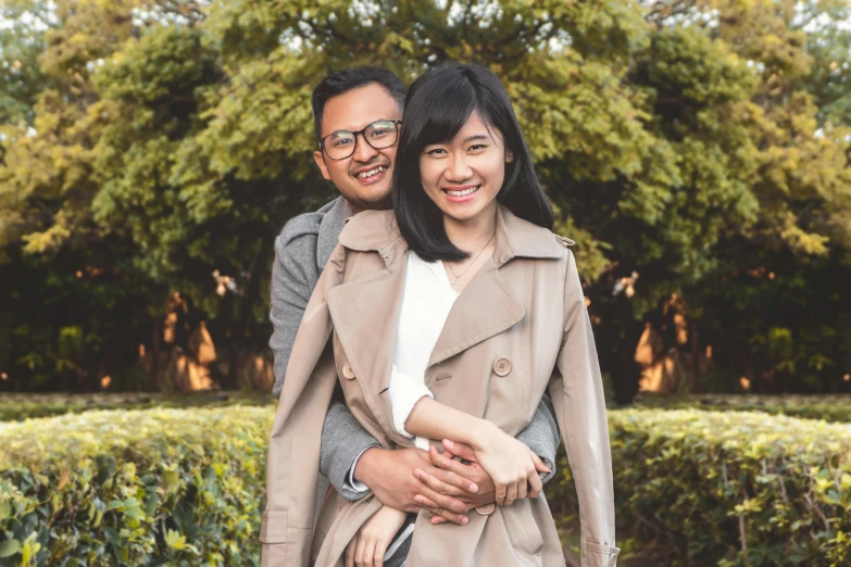 a man and woman hugging in front of some bushes