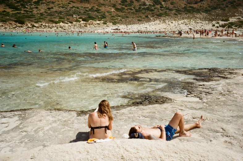 people standing on a beach with lots of blue water