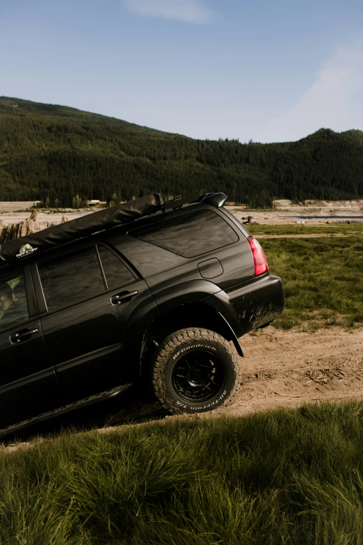 the truck is parked in the gravel beside a hilly area