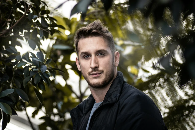 the man is posing by some green trees