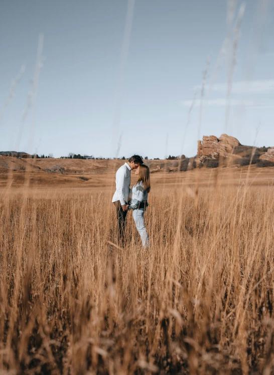 a man and woman standing in a field hugging