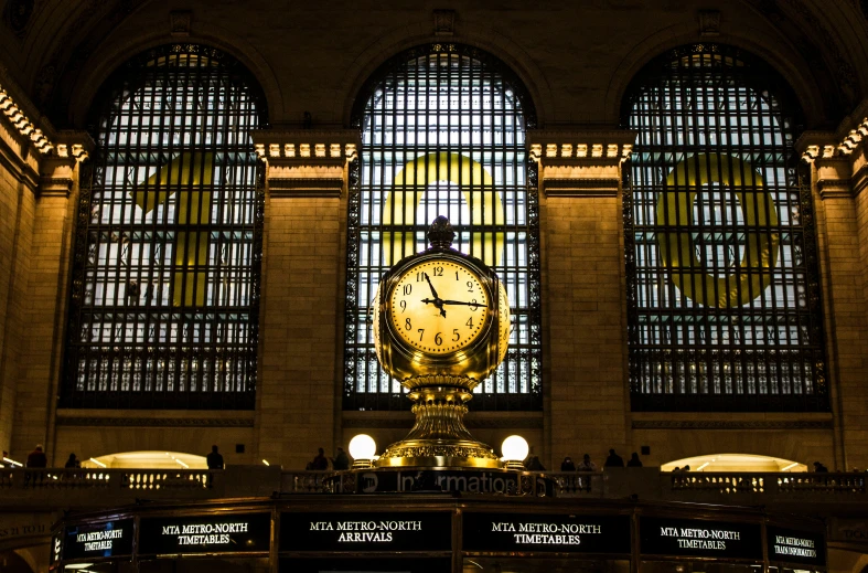 a large clock sits inside of an atrium