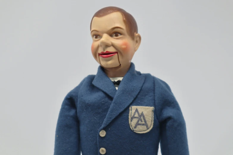 a very old, creepy doll head wearing blue coat and tie