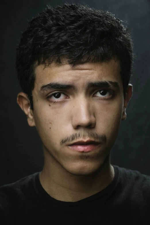 a man that is staring straight ahead in front of a black background
