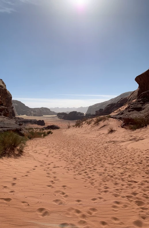 a person walking along a sandy path to some hills