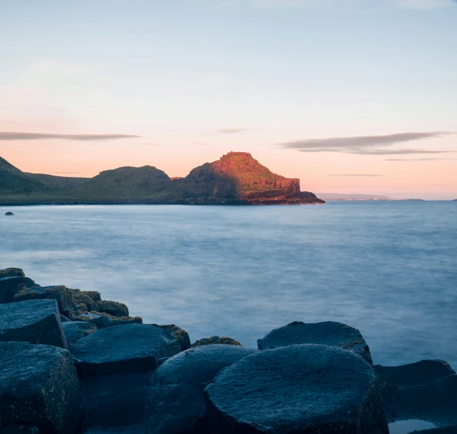 rocks on the shore line the sea at sunset