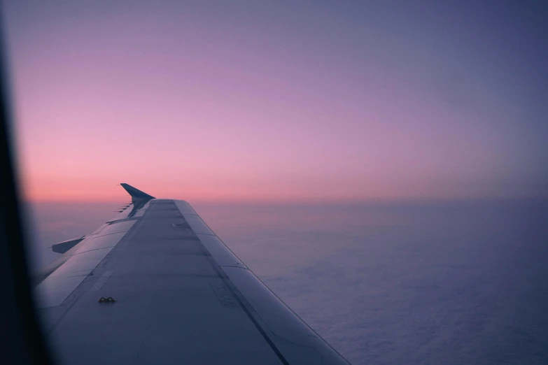 a view of the wing and engines of an airplane during sunset