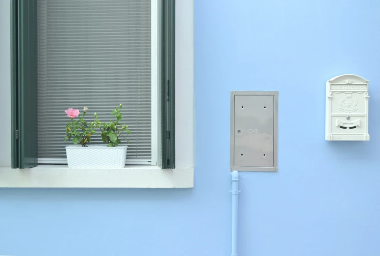 a bathroom window with a white curtain next to a plant