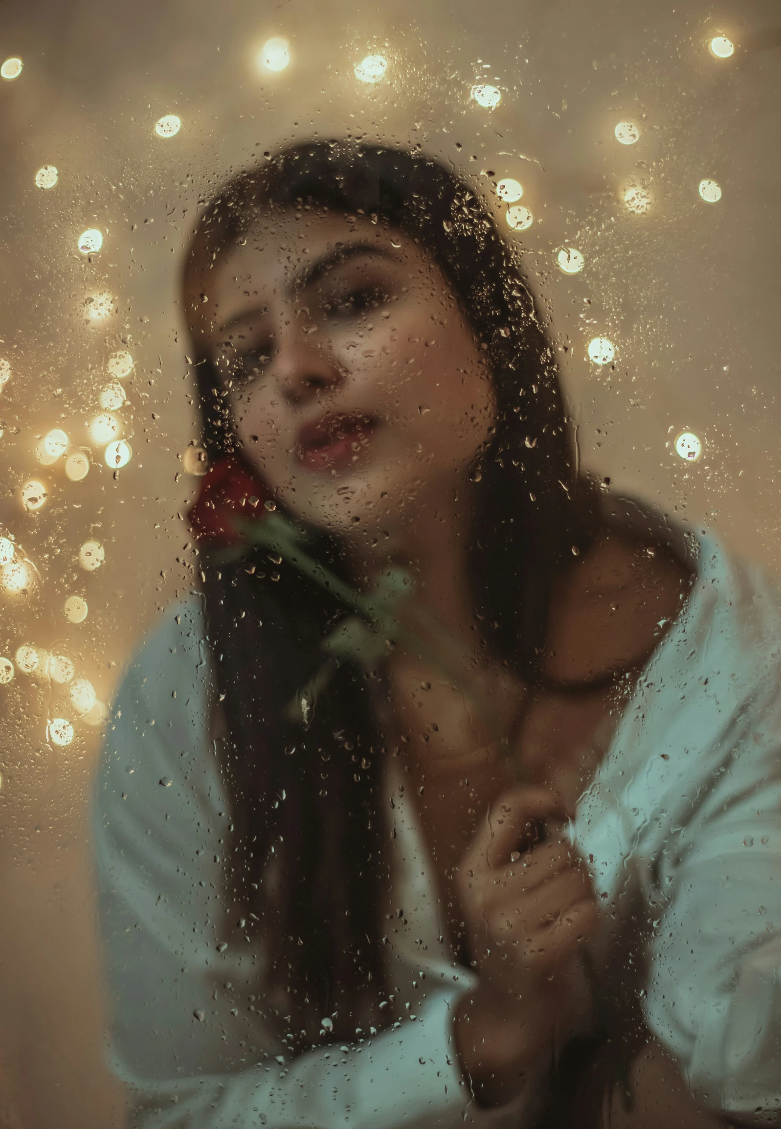 a beautiful woman standing behind a window covered in water drops