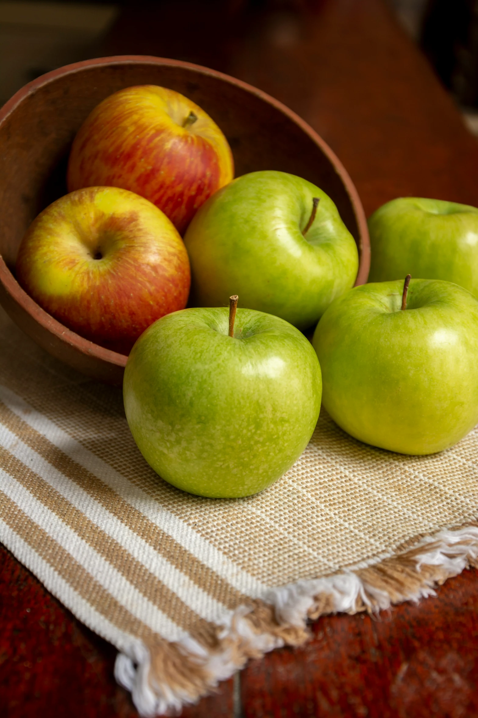 three green apples are in a bowl on a table