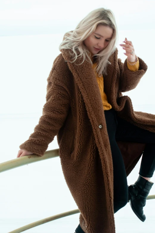 a woman is leaning against a rail wearing a fuzzy coat