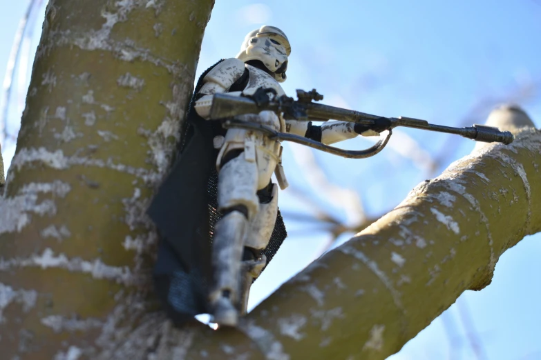 a storm trooper figure holding a gun up the trunk of a tree