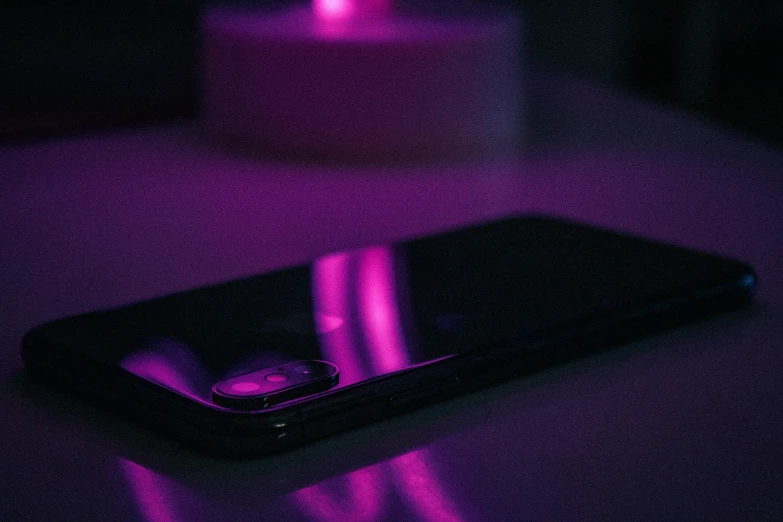 the cell phone is on a purple surface