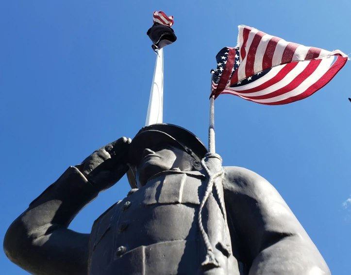 statue of a soldier holding a flag with a sky background