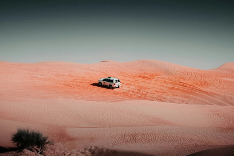 an suv in a desert area, with the desert sands below