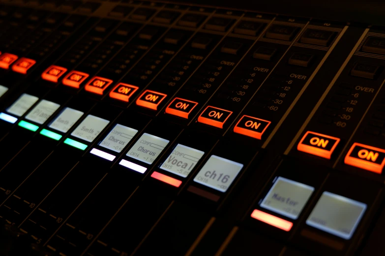 ons in a sound mixing desk illuminated by orange