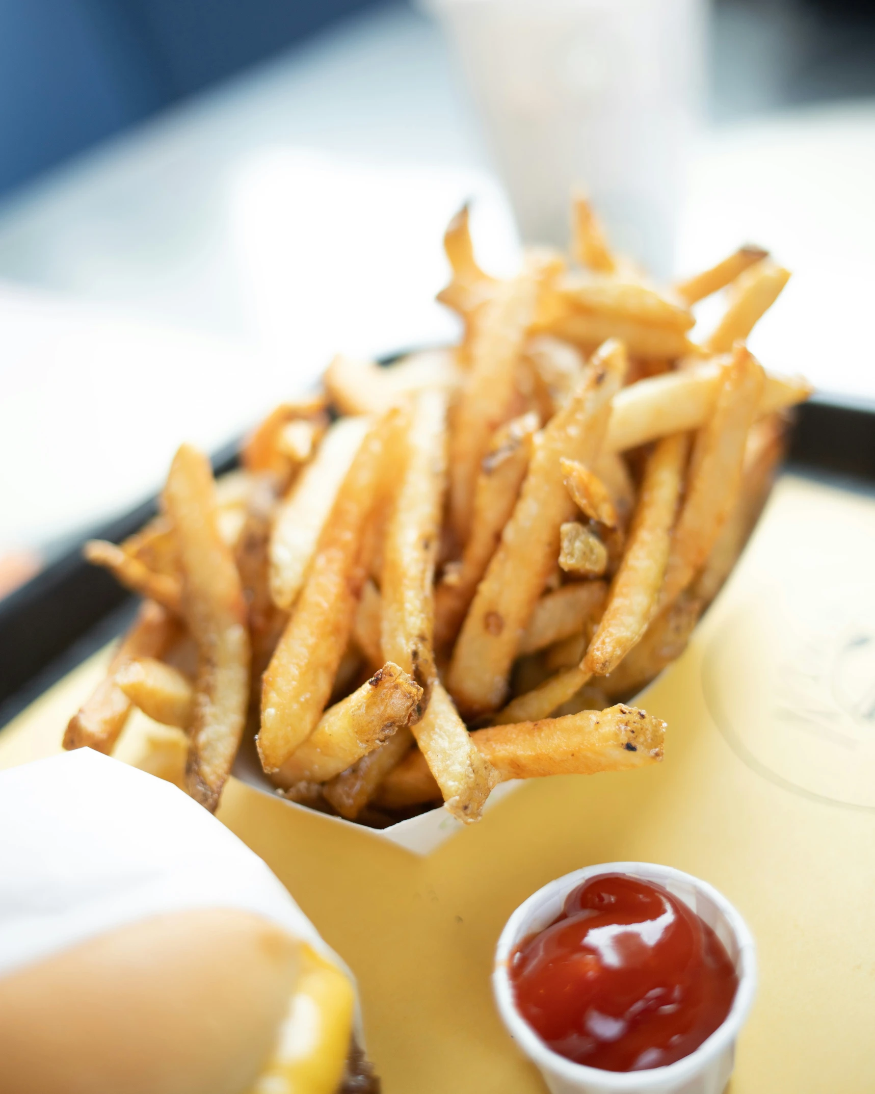 a container of fries on a tray with ketchup and mustard