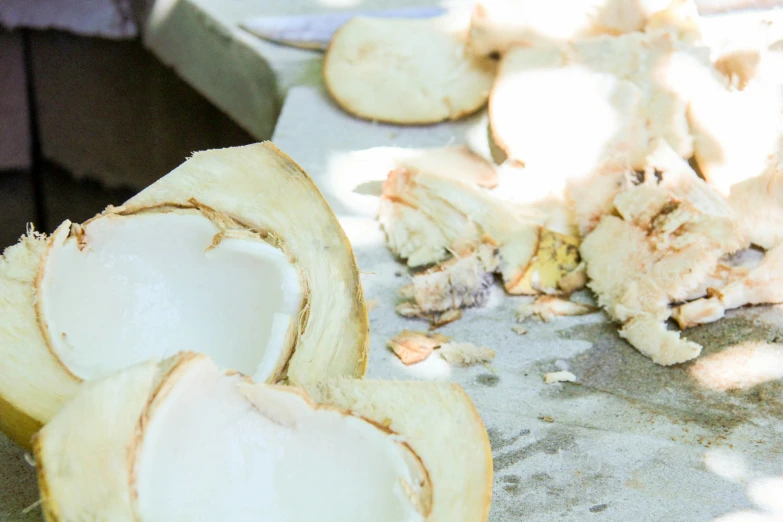 peeled, raw, unripe coconuts on a gray surface