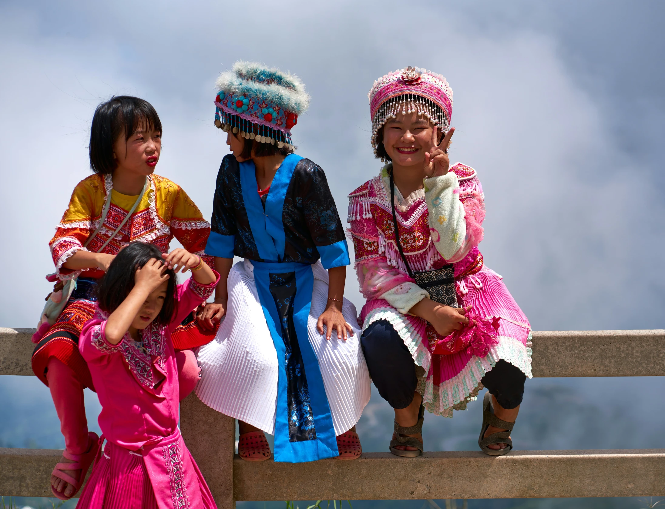 three children sitting on the ledge of a building together