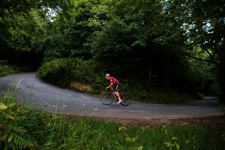 a bicyclist riding down a winding country road