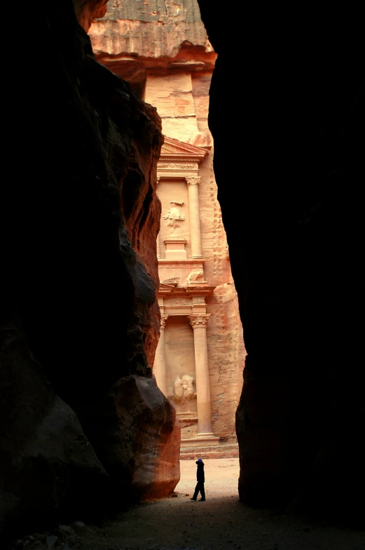 person standing in front of stone door in large canyon