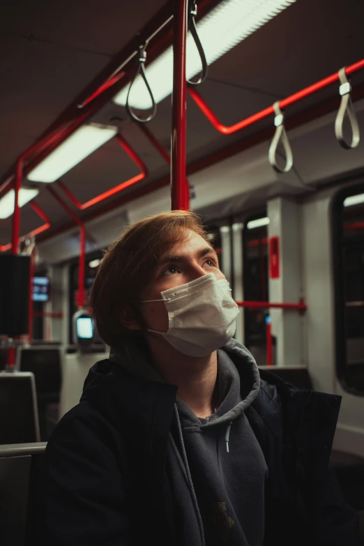 a man with a face mask on riding on a train