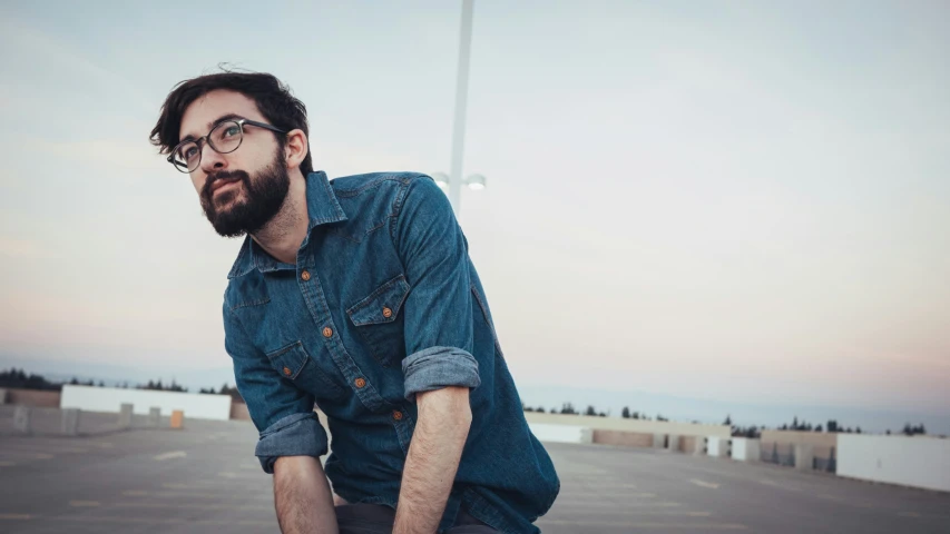 a man standing in a parking lot wearing glasses