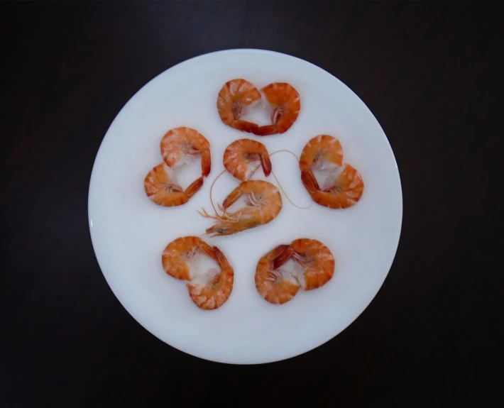 several small raw shrimp on a white plate