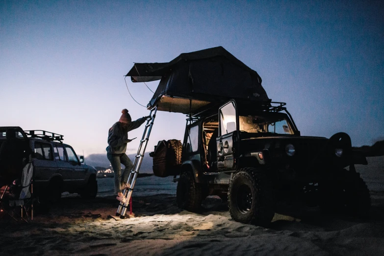 a man stands outside of a vehicle while holding his ladder