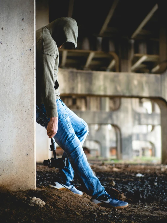 the man is leaning against the wall while holding his camera