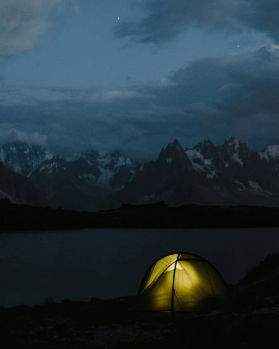 the bright green tent is near a mountain lake