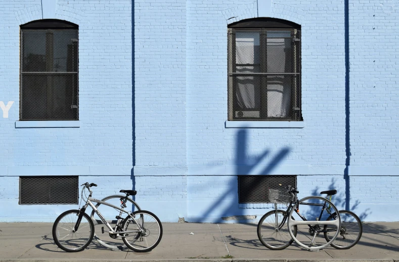 two parked bikes sitting in front of a blue building