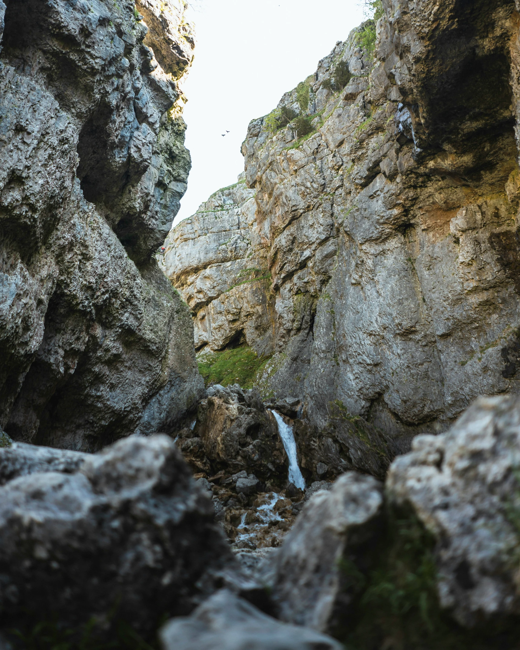 a view looking down at a mountain stream with some rocks and a cliff