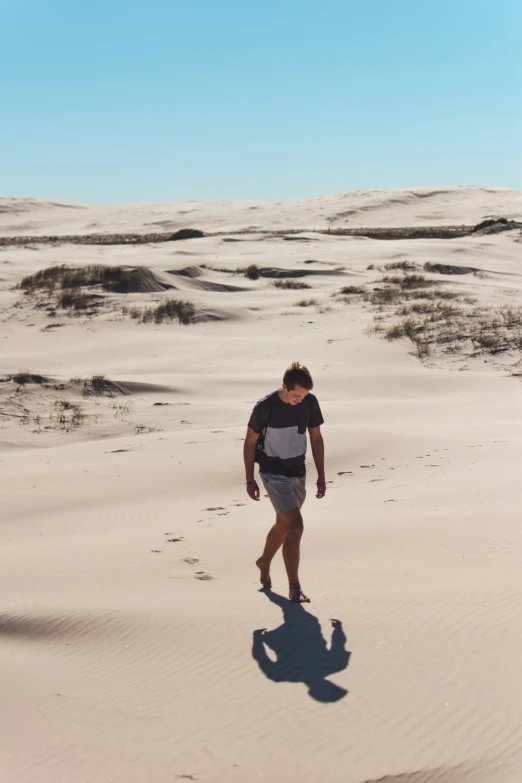 a man in a t - shirt is walking on a beach