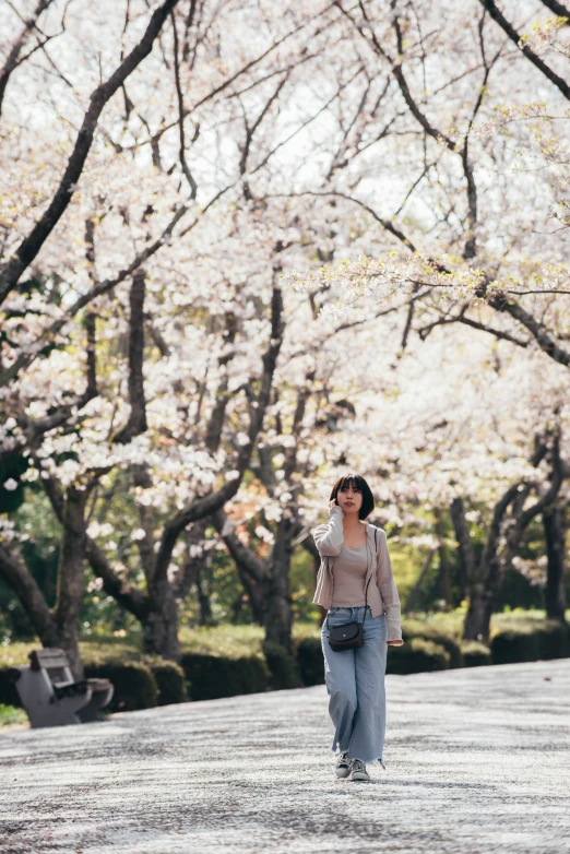 a woman standing next to some trees with white flowers